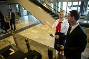 Female staff showing directions to businessman at airport terminal
