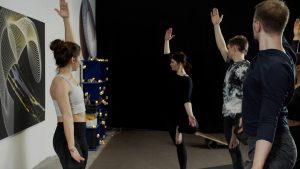 Group of slim people standing on one leg while doing yoga in studio